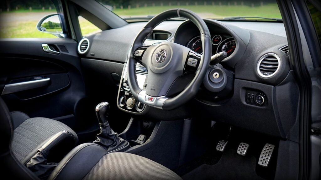Interior de um carro com câmbio manual e pedais à mostra: cabo de embreagem e pedal