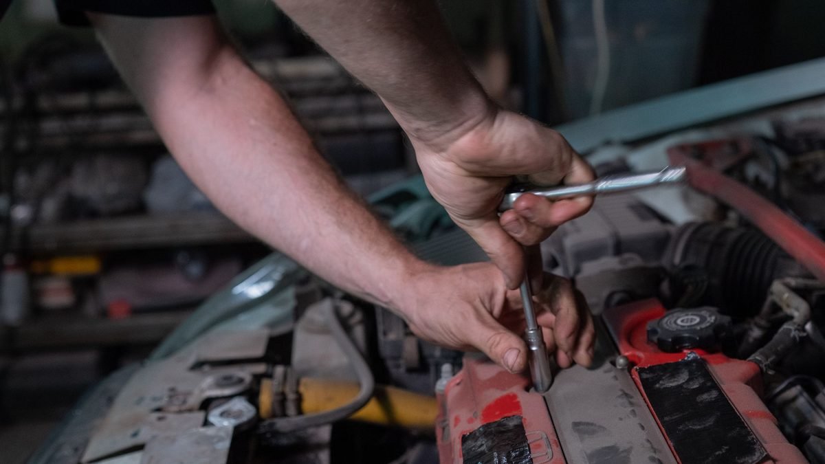 Mãos de um mecânico trabalhando no motor de um carro